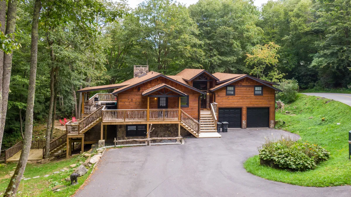 The wooden exterior of Moosey Creek Lodge with a welcoming front deck, surrounded by tall trees. The deck is an ideal spot for outdoor meals and gatherings, and the tranquil driveway highlights the home’s peaceful, natural setting.