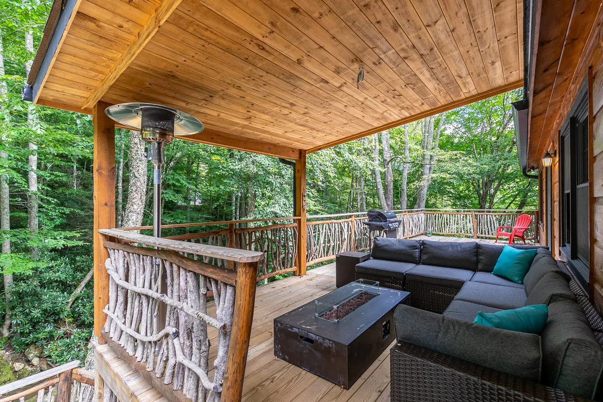 An inviting outdoor seating area set around a stone fire pit, framed by greenery and a built-in grill. The space is ready for social gatherings, evening storytelling, and stargazing, with comfortable chairs encircling the warmth of the fire.