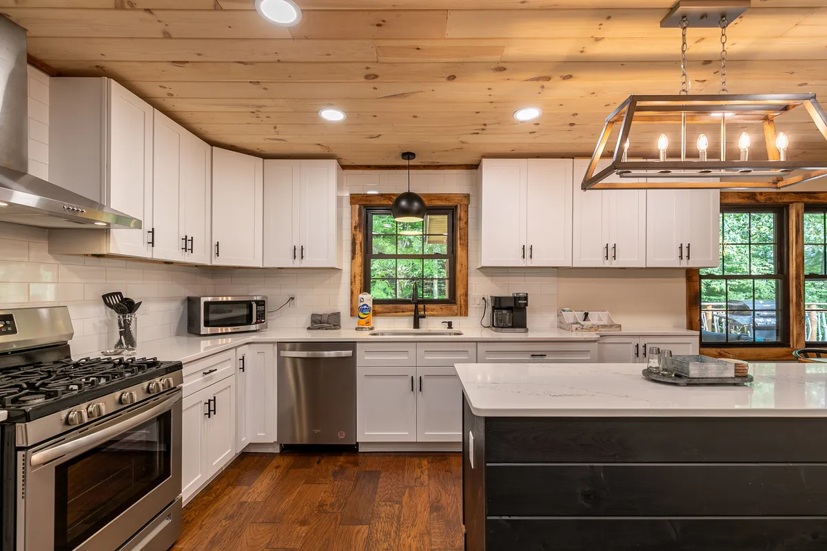 A chef-inspired kitchen with stainless steel appliances, a spacious island countertop, and a sunlit window framing a mountain view. The kitchen is designed for cooking, gathering, and entertaining, echoing the space’s suitability for family feasts and group culinary activities.