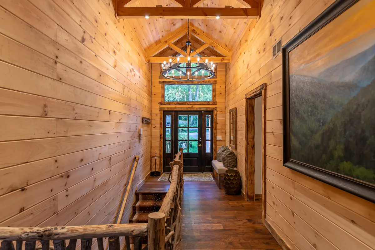 The lodge's entrance hall, featuring a warm chandelier, wooden walls, front doors, and artwork. The lighting and decor create a welcoming atmosphere that sets the tone for a romantic getaway.