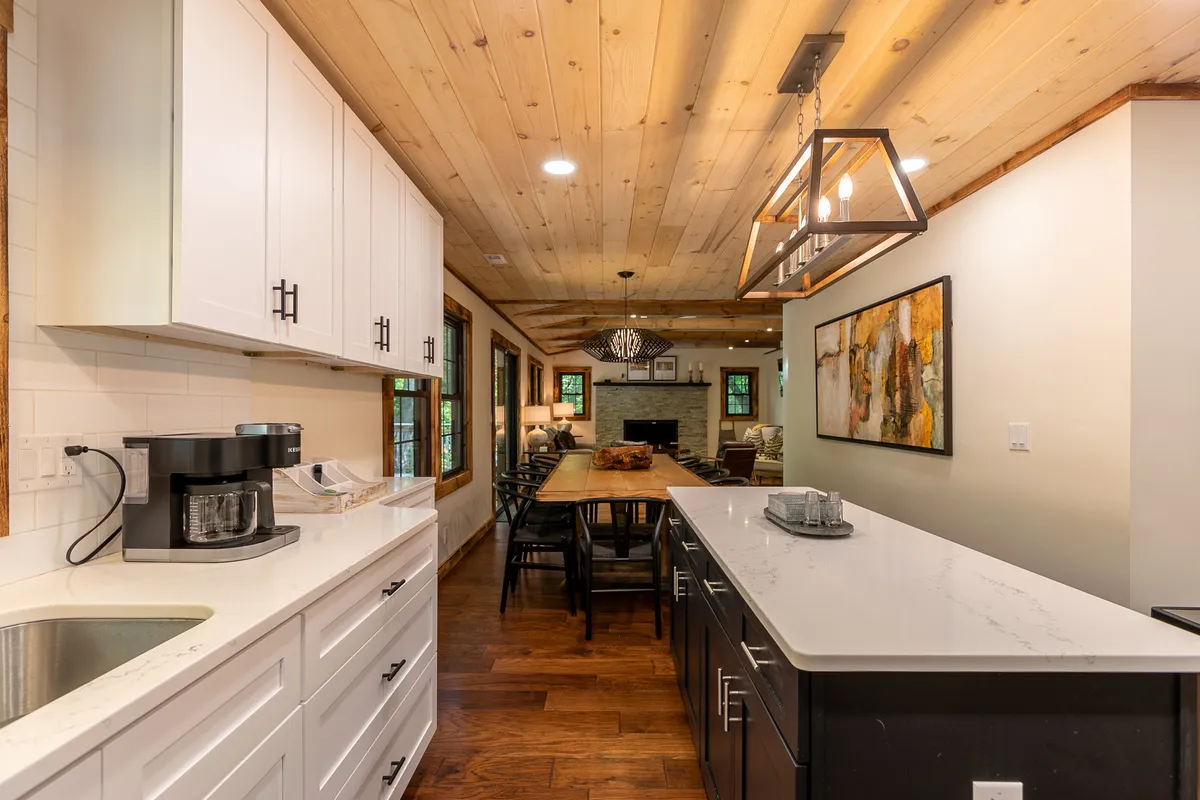 A spacious kitchen and dining area featuring a kitchen island, dining table, stylish lighting, and a fireplace. The scene conveys a sense of gathering, sharing meals, and celebrating together.